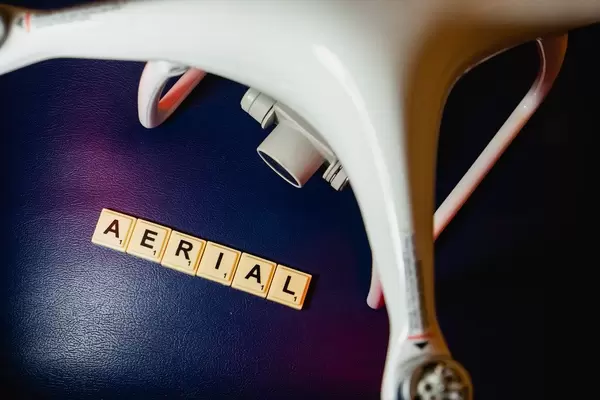 Scrabblespielsteine zeigen das englische Wort "Aerial" für Luft, neben einer Drohne für Luftaufnahmen