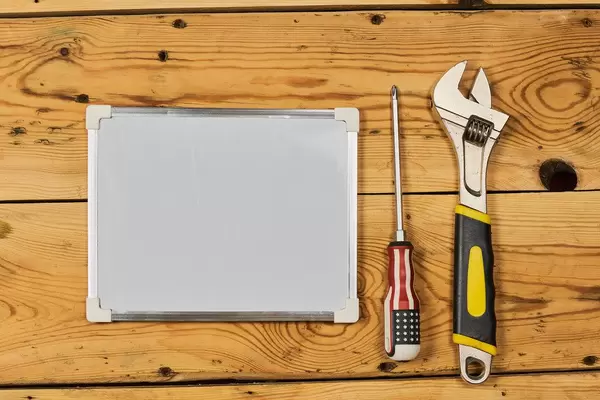Screwdriver, adjustable wrench and whiteboard with copy space on the wood