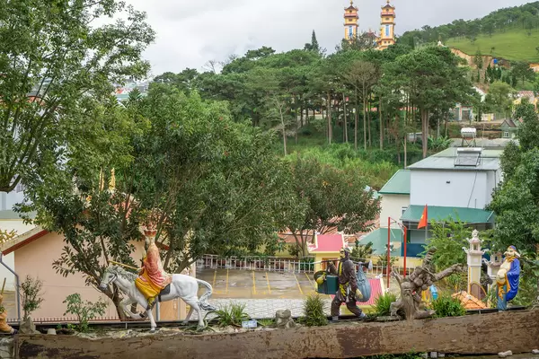 Sculptures of Buddhist Characters on a Wall with Houses and a Church in the Background