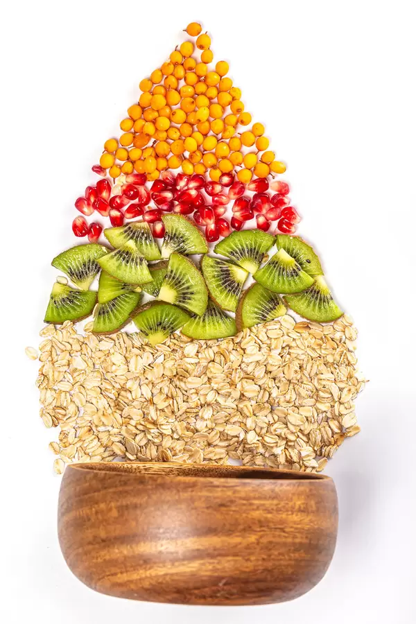 Sea buckthorn berries, pomegranate, kiwi and oatmeal with bowl on white