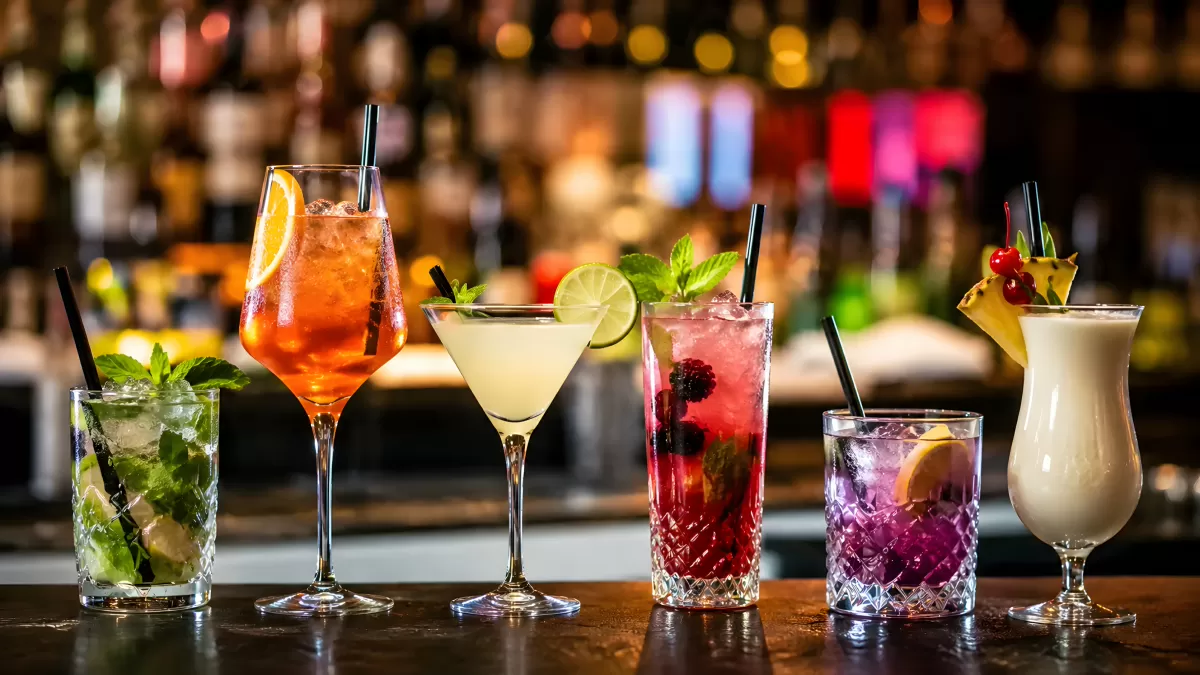 Sechs bunte Cocktails auf einer Bartheke im Club