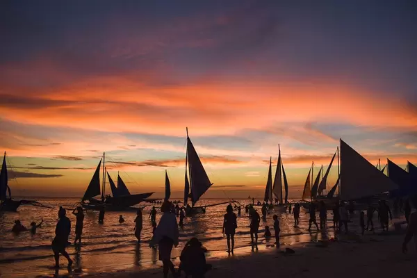 Segelboote legen im Sonnenuntergang zur goldenen Stunde am Strand von Boracay an