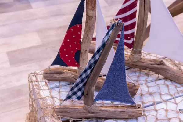 Segelbote hergestellt aus Ästen und Schnüren mit kleinen Stoffsegeln auf Holzkiste mit Fischernetz