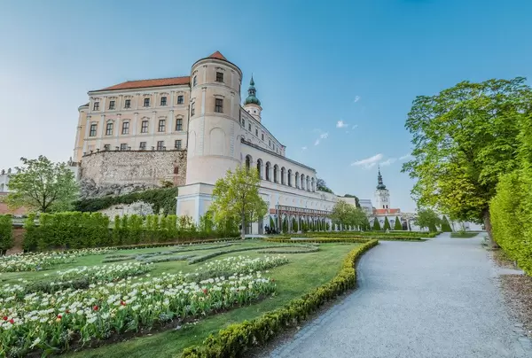 Seitenansicht auf das Schloss Mikulov mit grüner Gartenanlage und Blumenbeet