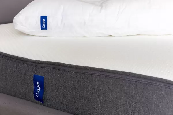 Seitenansicht der ergnomische Casper-Matratze in weiß und grau mit Casper-Kopfkissen