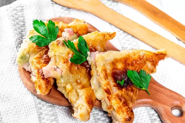 Selbstgemachte Khachapuri, in dreieckige Stücke geschnitten, auf einem kleinen Holzbrettchen