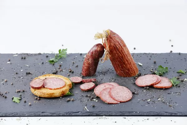 Selbstgemachte rote Wurst: Salami in Scheiben geschnitten, auf einem Schiefersteinbrettchen