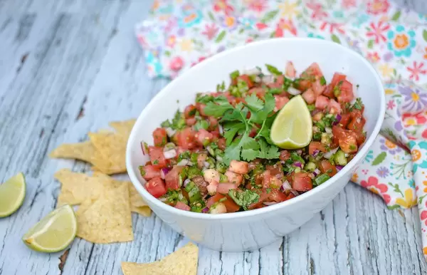 Selbstgemachte Salsa, mit Minze, Limette und Tomaten, neben Nachos auf einem rustikalen, alten Küchentisch