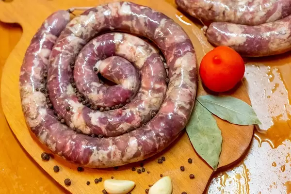 Selbstgemachte Wurstschnecke mit Tomate, Pfeffer und Lorbeer auf Holzbrett