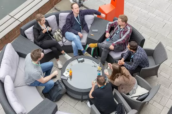 Self-employed and participants of the Barcamp OMWest19 of AXA in Cologne, taking a break and talking on round rattan furniture on a terrace