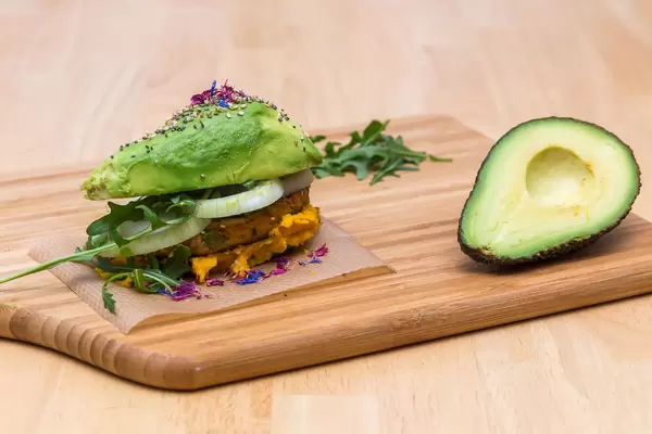 Self-made Avocado burger with veggie hamburger, Humus and Onions