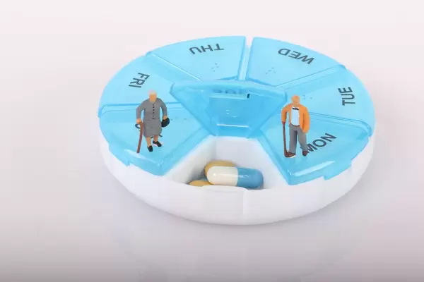 Senior couple standing on pill reminder box