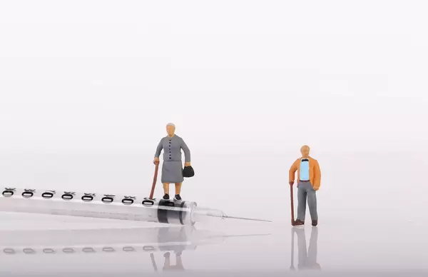 Senior couple with syringe on white background