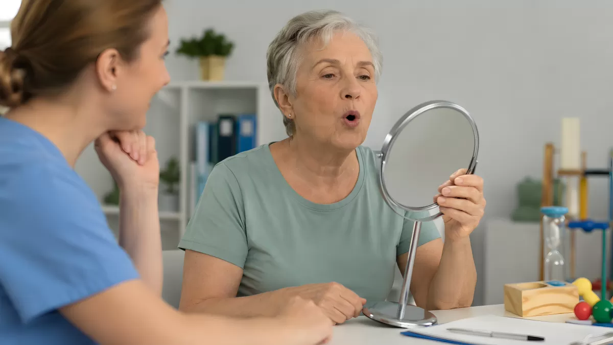 Seniorin bei Sprachtherapie mit Spiegel und Therapeutin