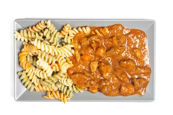 Served cooked colorful macaroni on the plate with meat goulash