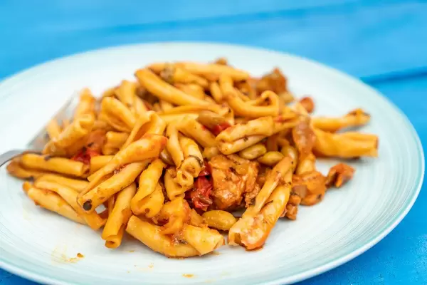 Served Pasta with Tuna on the white plate above blue wooden table (Flip 2020)