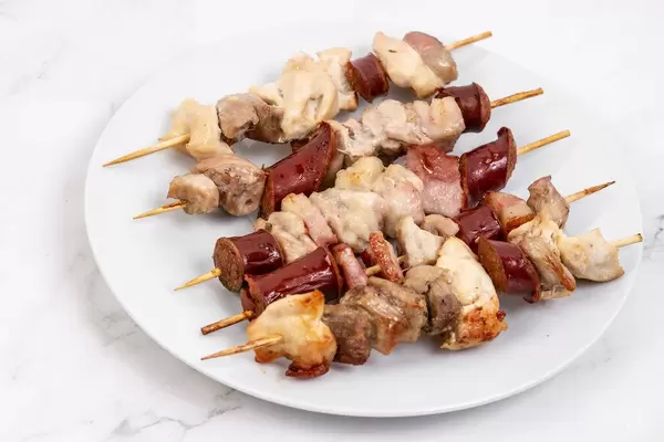 Served sliced Sausage Bacon and Meat on the wooden grill stick