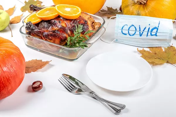 Served table on the day of Thanksgiving and medical mask with the inscription covid