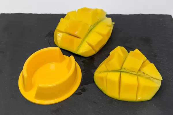 Servierfertige Mangohälften auf schwarzer Schieferplatte