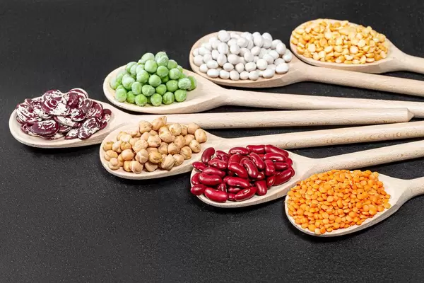 Set lentils, chickpeas, peas and beans of different colors in wooden spoons on black background (Flip 2019)