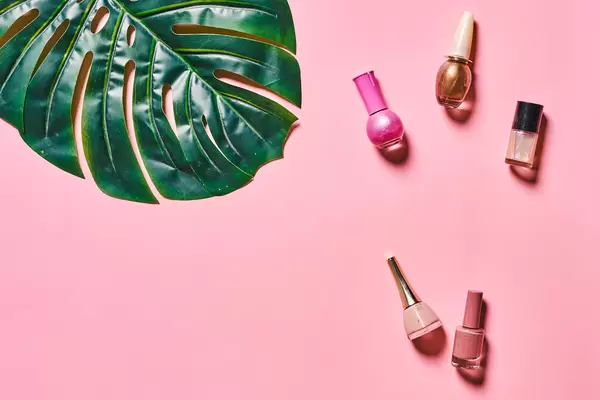 Set of bright nail polish gels and tropical palm leaf