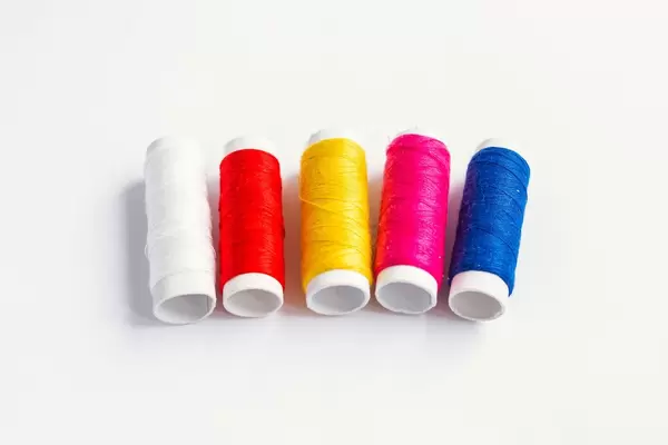 Set of colorful sewing threads on white background