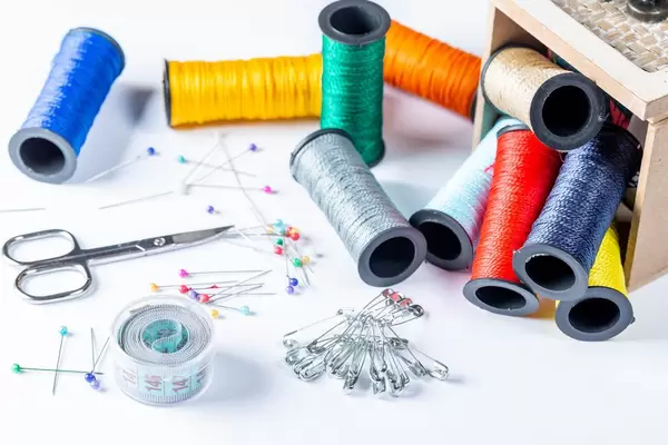 Set of colorful threads, needles, pins and scissors with measuring tape