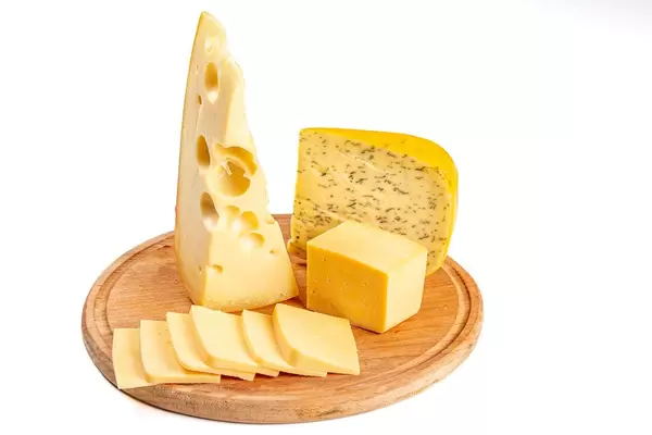 Set of different delicious cheeses on a round wooden kitchen board