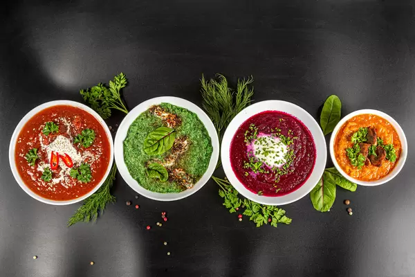 Set of different multi-colored soups on a black background