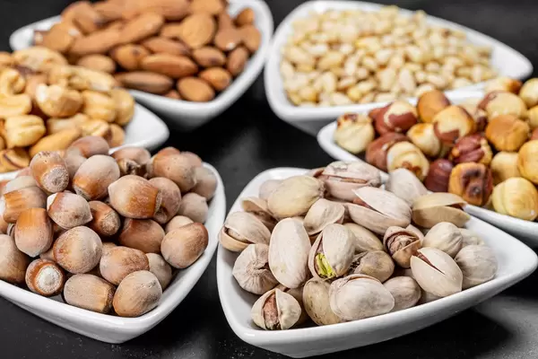 Set of different nuts in white bowls on a black background (Flip 2020)