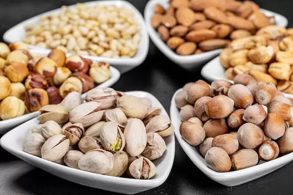 Set of different nuts in white bowls on a black background