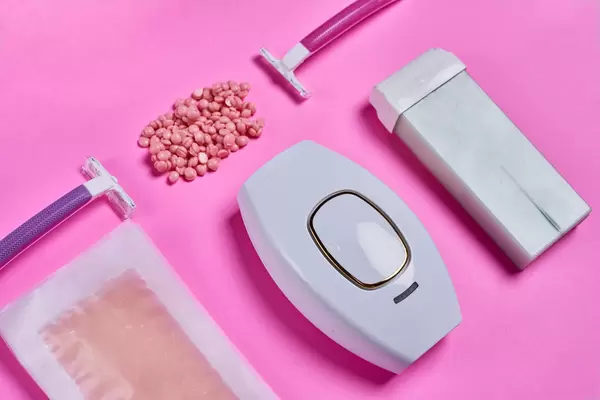 Set of epilation tools and products on pink background