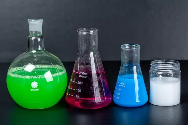 Set of laboratory glassware with chemical multi-colored solutions on a black background