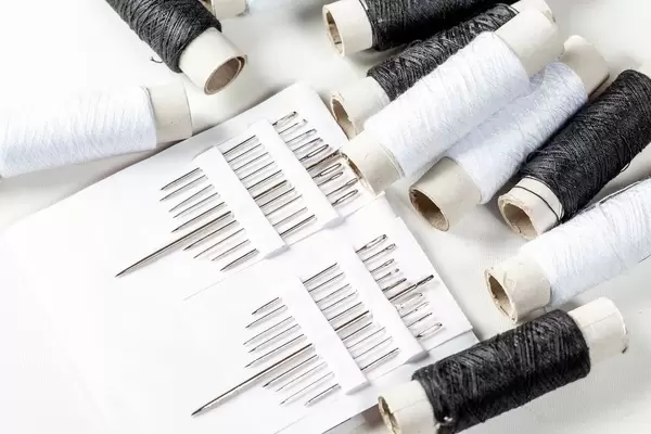 Set of needles of different sizes with black and white threads