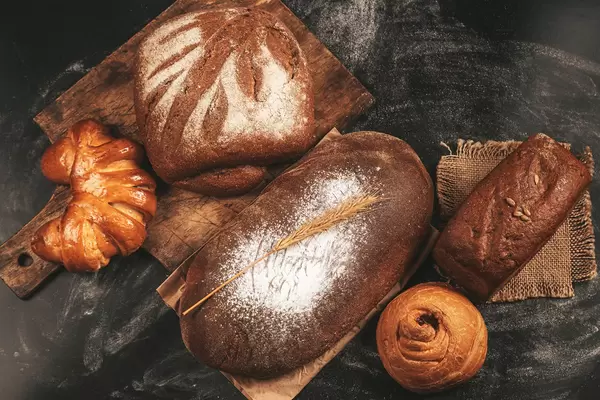Set of rye bread and buns on a dark background, top view