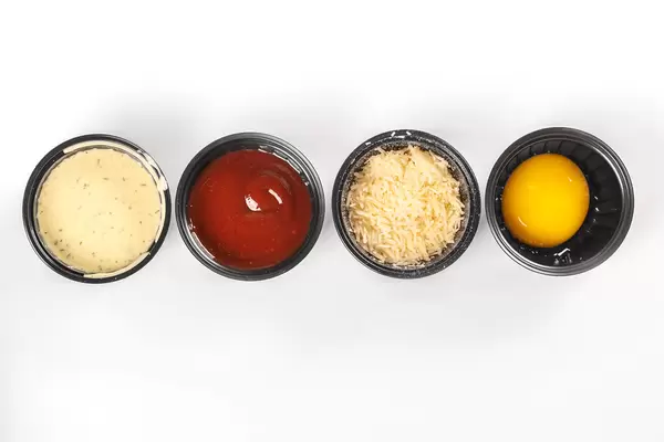 Set of sauces, grated parmesan cheese and egg yolk in black bowls, top view