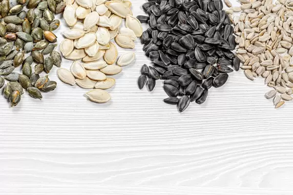Set of sunflower seeds and pumpkin on white wooden background