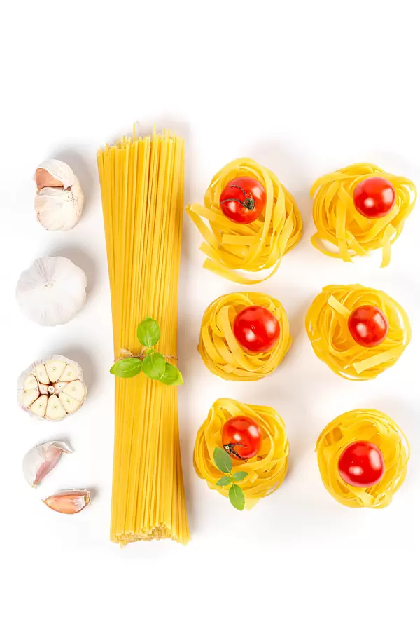 Set with spaghetti and fettuccine pasta, garlic, basil and tomatoes, top view