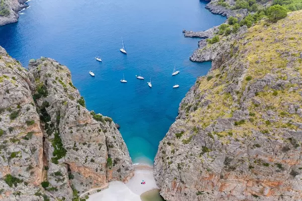 Seven sailboats and one motor boat in the bay of Sa Calobra on the northwest coast of Majorca, drone pic