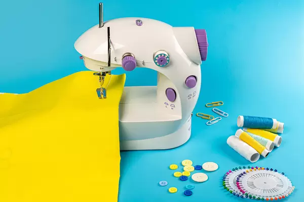 Sewing machine with yellow fabric on blue background