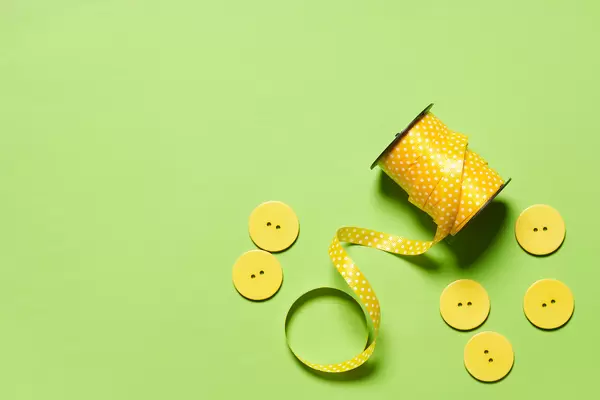 Sewing spool of thread and buttons on the green