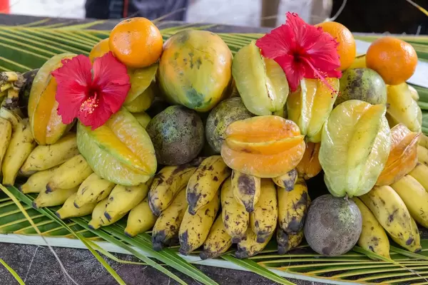 Seychellen-Obst auf Palmenblätter gestapelt, mit Bananen, Mangos, Sternfrucht und Orangen am Anse Source d'Argent Strand auf La Digue