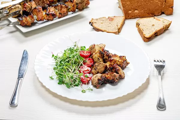 Shashlik with micro greens radish and tomato slices on a white wooden table with a knife and fork (Flip 2019)