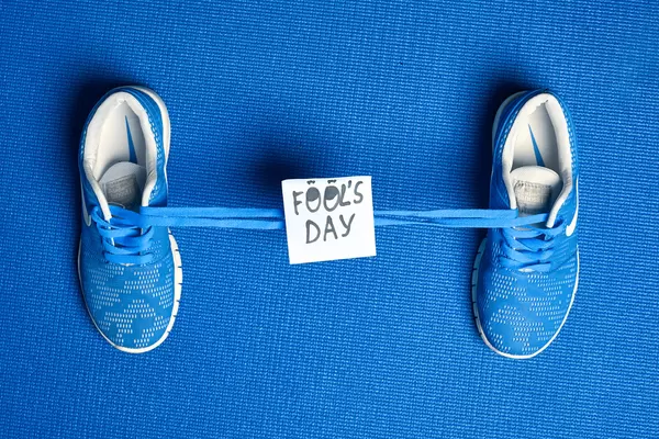 Shoes tied together and note with phrase - Fools day on blue background