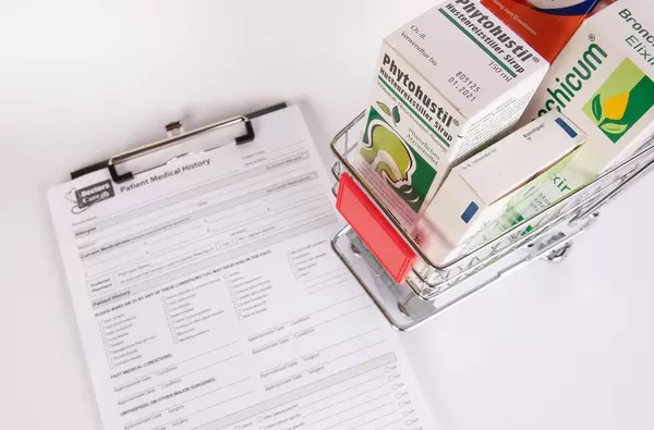 Shopping cart filled with medicines next to a Patient Medical History form