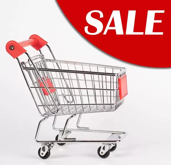 Shopping cart isolated on white with a sale advertisement in the background