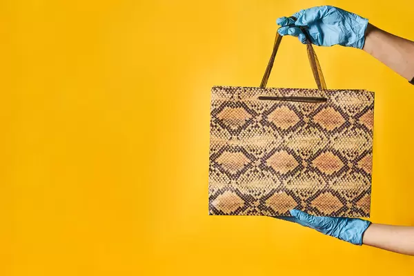 Shopping consultant in protective medical gloves holding a shopping bag