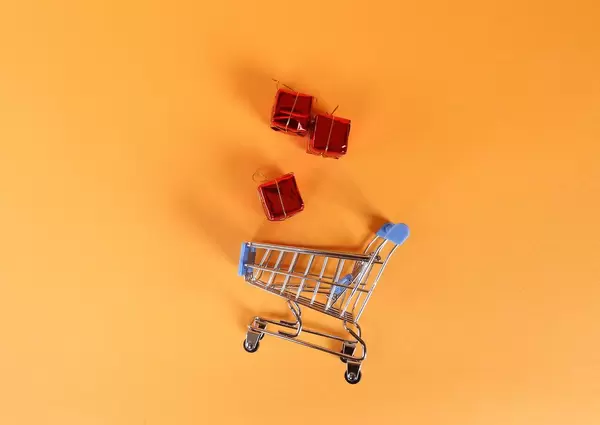 Shopping trolley with gifts on orange background