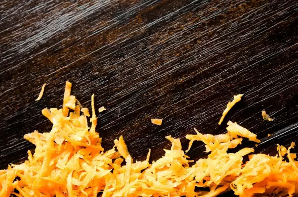 Shredded carrot over wood background