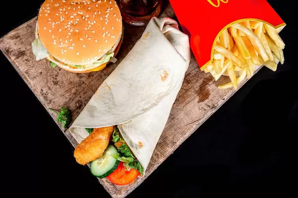 Shrimp roll, fries and burger with cola, top view
